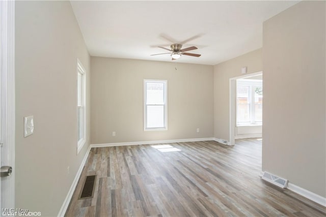 empty room with a healthy amount of sunlight, visible vents, and wood finished floors