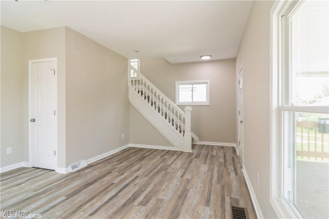 spare room with visible vents, baseboards, stairway, and light wood finished floors