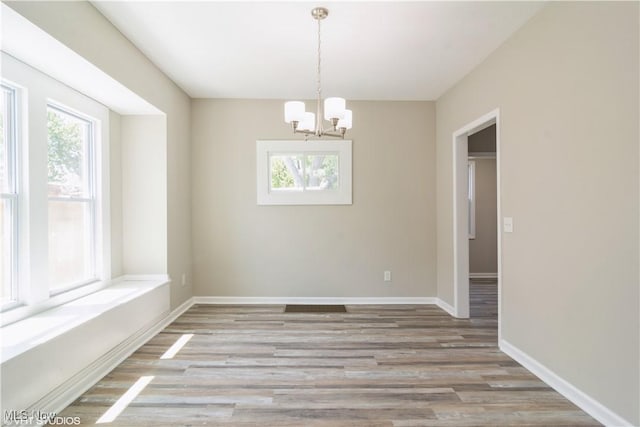 unfurnished room featuring light wood-type flooring, plenty of natural light, and baseboards