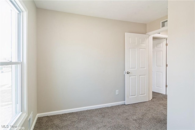 empty room with baseboards, visible vents, and light colored carpet