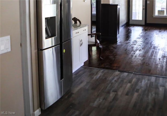 kitchen with light stone counters, dark hardwood / wood-style floors, white cabinetry, and stainless steel refrigerator