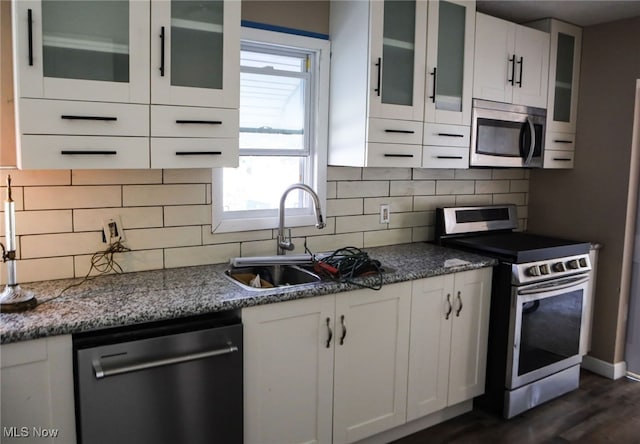 kitchen with stainless steel appliances, backsplash, stone counters, white cabinets, and dark hardwood / wood-style floors