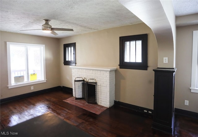 unfurnished living room with ceiling fan, a fireplace, hardwood / wood-style flooring, and a healthy amount of sunlight