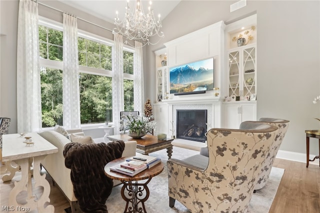 living area featuring a notable chandelier, light hardwood / wood-style flooring, and vaulted ceiling