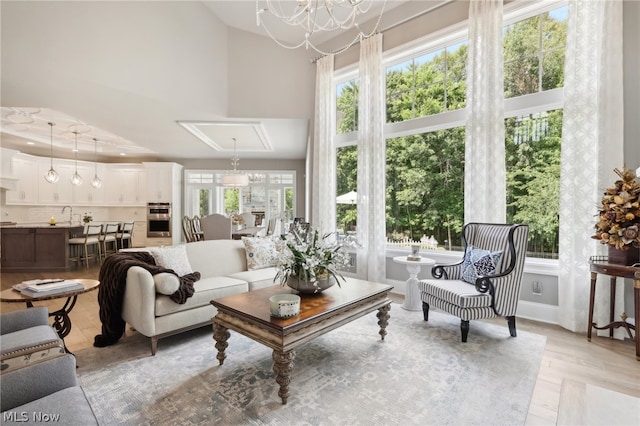 living room with a notable chandelier, sink, a towering ceiling, and a healthy amount of sunlight