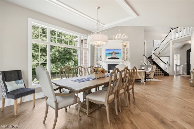 dining space with a notable chandelier, a raised ceiling, and light hardwood / wood-style floors