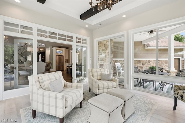 sunroom / solarium featuring ceiling fan with notable chandelier