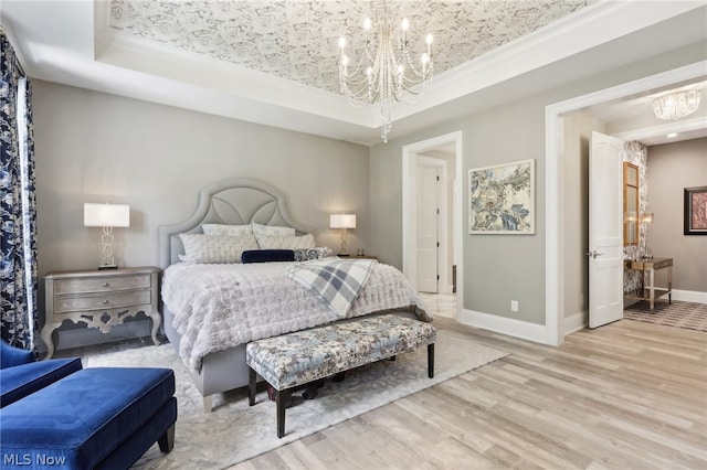 bedroom with a raised ceiling, light hardwood / wood-style flooring, and an inviting chandelier