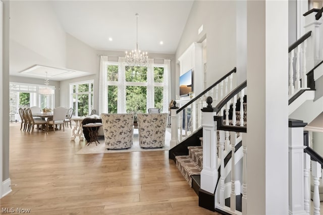 interior space featuring an inviting chandelier, a towering ceiling, and light hardwood / wood-style floors