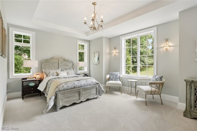 carpeted bedroom featuring a chandelier and a tray ceiling