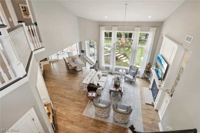 living room featuring an inviting chandelier, a high ceiling, and light hardwood / wood-style floors