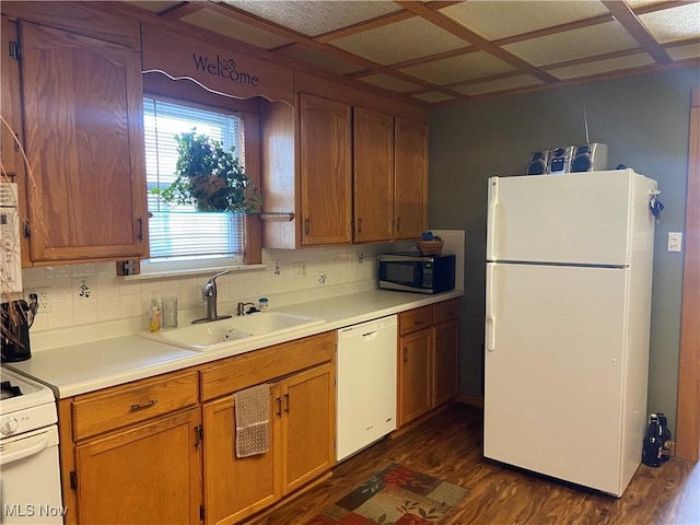 kitchen featuring dark hardwood / wood-style flooring, white appliances, tasteful backsplash, and sink