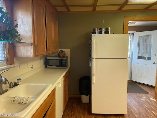 kitchen featuring white appliances, dark hardwood / wood-style floors, backsplash, and sink