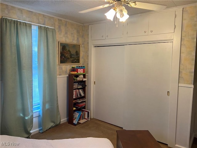 bedroom featuring wood walls, ceiling fan, ornamental molding, carpet floors, and a closet