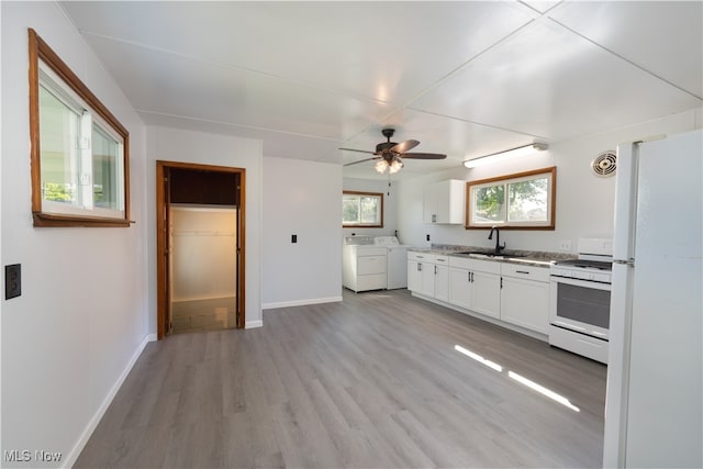 kitchen featuring white appliances, white cabinets, sink, light hardwood / wood-style floors, and washing machine and dryer