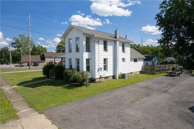 view of side of property with a lawn and central AC unit