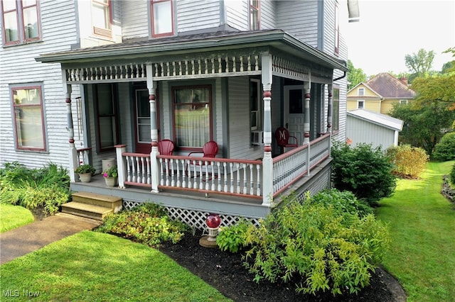 view of exterior entry featuring a yard and a porch