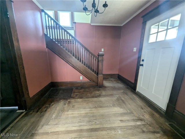 entrance foyer featuring a notable chandelier, a wealth of natural light, parquet floors, and crown molding