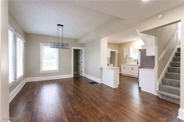 unfurnished dining area featuring a textured ceiling, sink, and dark hardwood / wood-style flooring