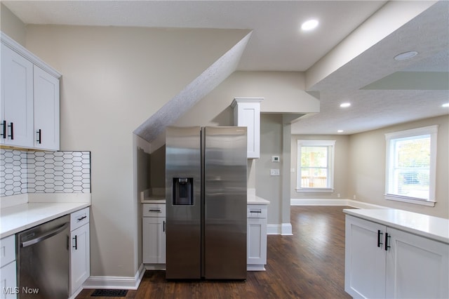 kitchen featuring dark hardwood / wood-style floors, backsplash, white cabinetry, appliances with stainless steel finishes, and a textured ceiling