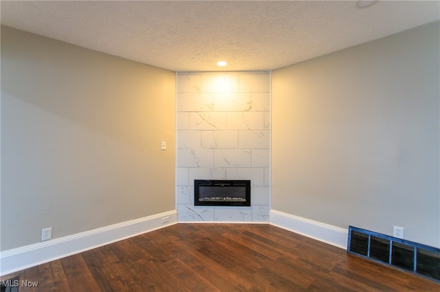 unfurnished living room with a textured ceiling, a tiled fireplace, and hardwood / wood-style floors