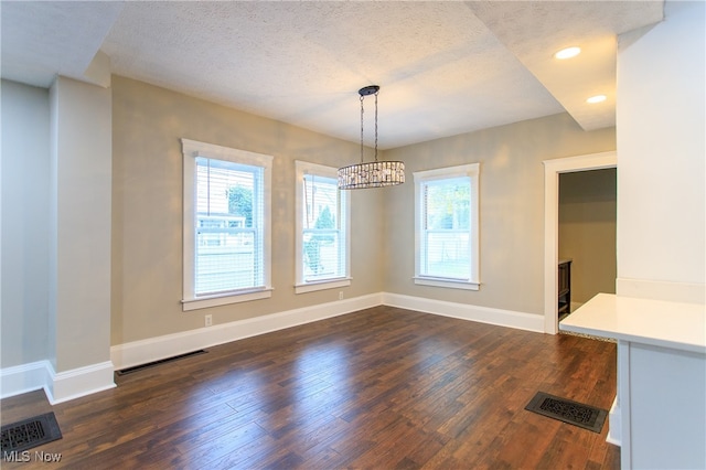 unfurnished dining area featuring a textured ceiling and dark hardwood / wood-style flooring