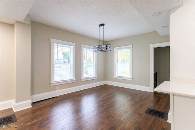 unfurnished dining area featuring a textured ceiling and dark hardwood / wood-style flooring