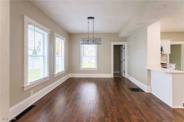 unfurnished dining area featuring dark wood-type flooring and a textured ceiling