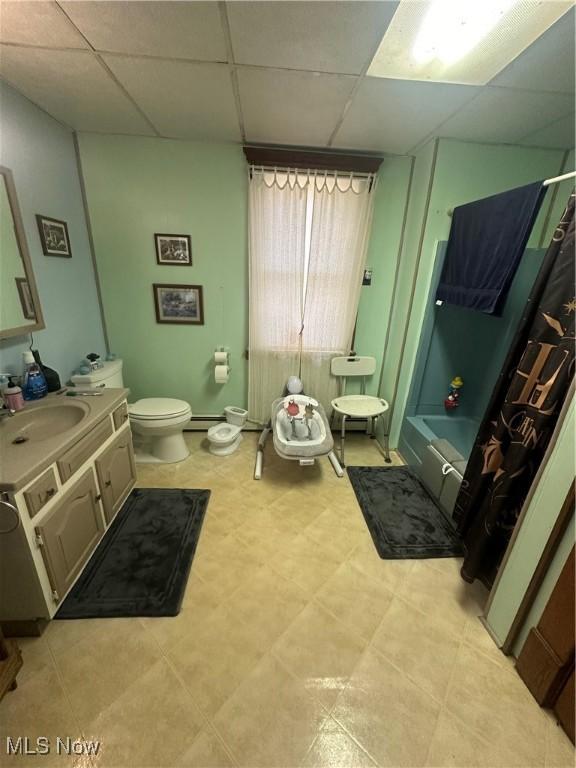 full bathroom featuring toilet, shower / bath combo, tile patterned floors, a drop ceiling, and vanity