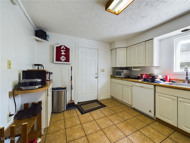 kitchen featuring dishwasher, sink, a textured ceiling, and light tile patterned flooring