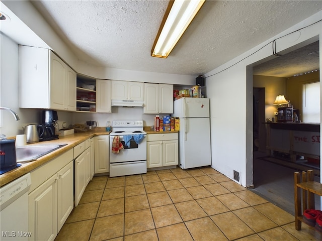 kitchen featuring light tile patterned floors, a textured ceiling, and white appliances