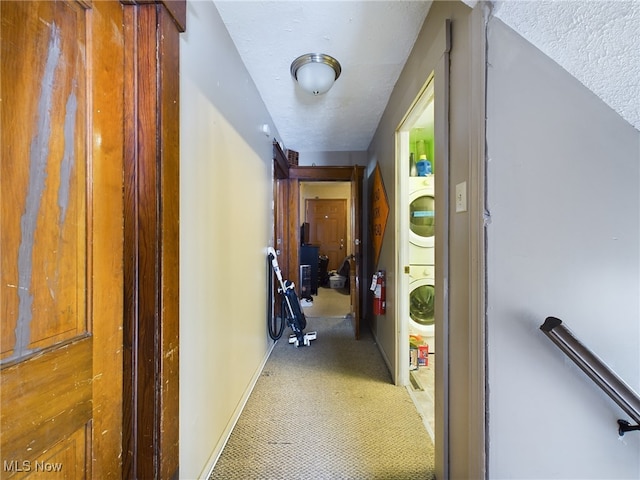 hallway with a textured ceiling and stacked washer and dryer