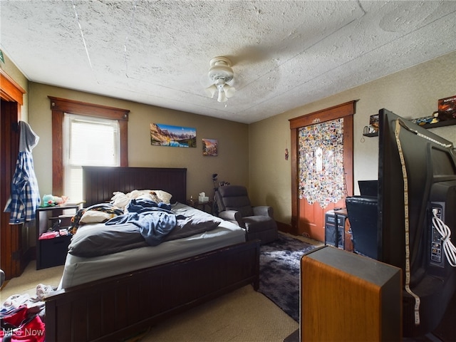 carpeted bedroom featuring ceiling fan and a textured ceiling