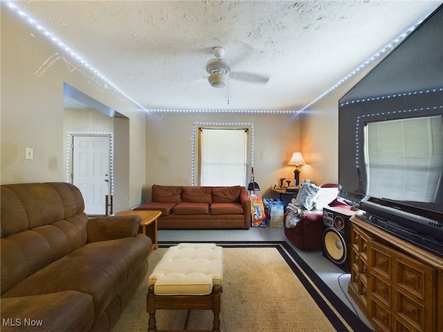 living room with ceiling fan and a textured ceiling