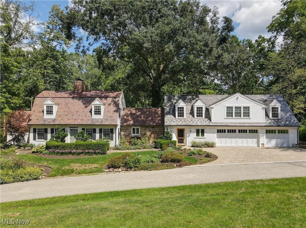 cape cod-style house featuring a garage and a front lawn