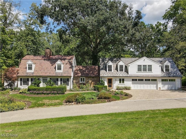 cape cod-style house featuring a garage and a front lawn