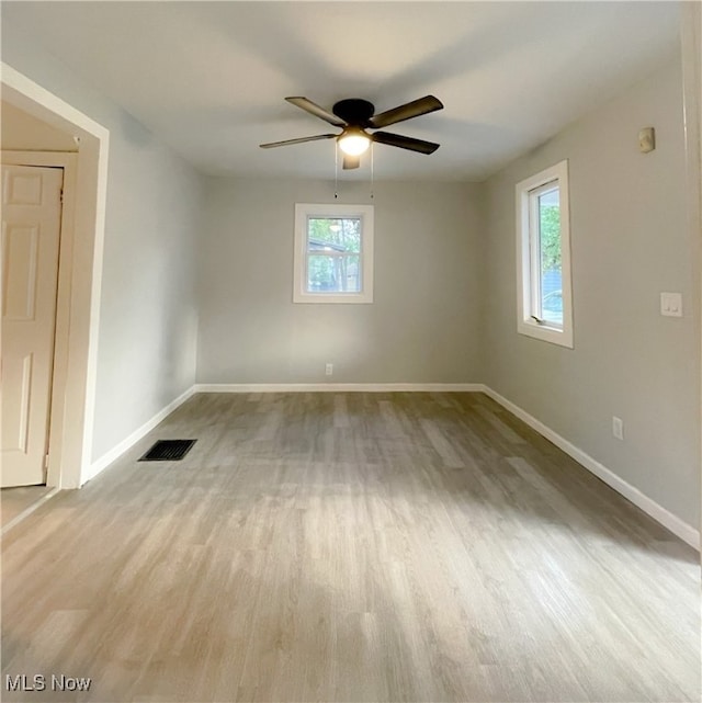 spare room featuring ceiling fan, light wood-type flooring, and a healthy amount of sunlight