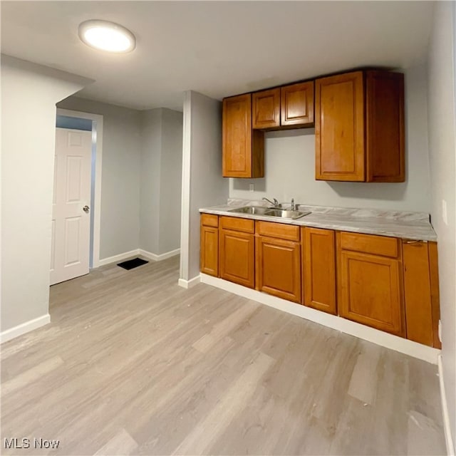 kitchen with sink, light hardwood / wood-style floors, and light stone counters