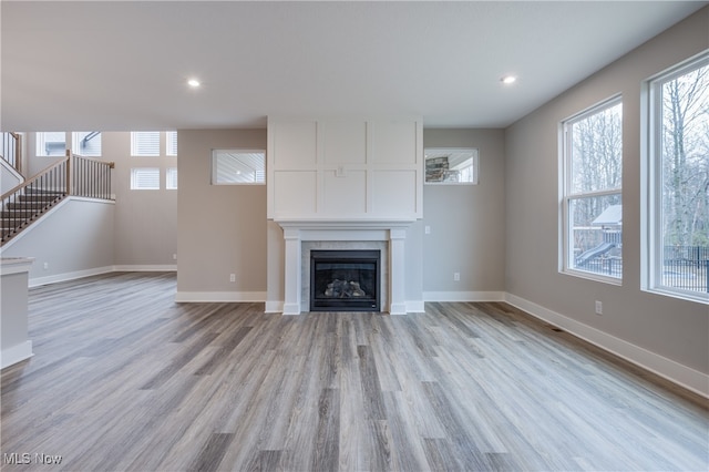 unfurnished living room featuring a tile fireplace and light wood-type flooring