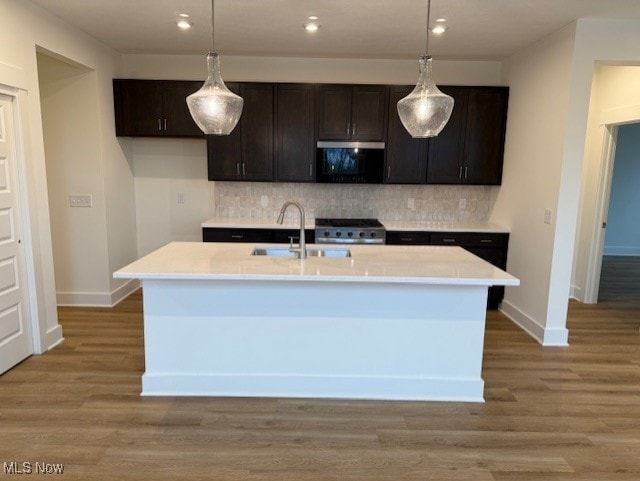 kitchen featuring decorative light fixtures, stainless steel appliances, and an island with sink