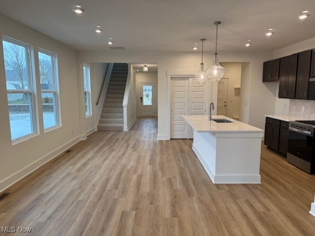 kitchen with sink, stainless steel stove, light hardwood / wood-style flooring, and a wealth of natural light