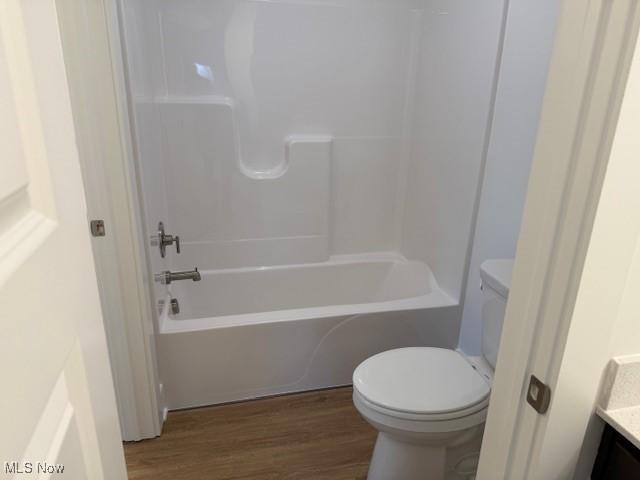 full bathroom with vanity, hardwood / wood-style flooring, toilet, and washtub / shower combination