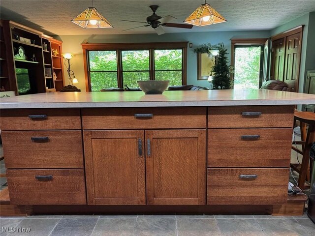 kitchen featuring ceiling fan, hanging light fixtures, and a textured ceiling