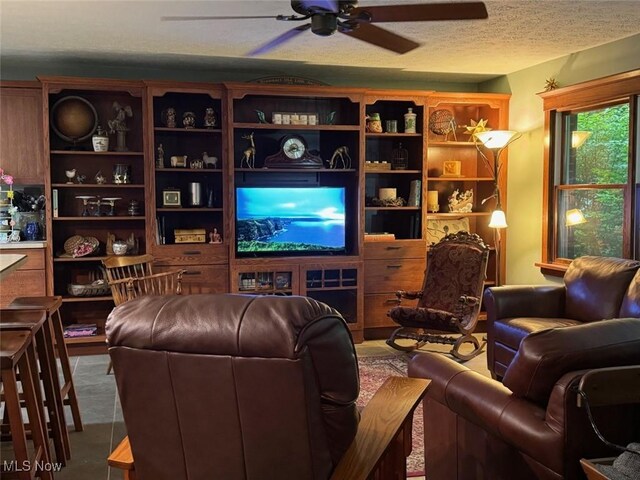 living room with tile patterned flooring, ceiling fan, and a textured ceiling