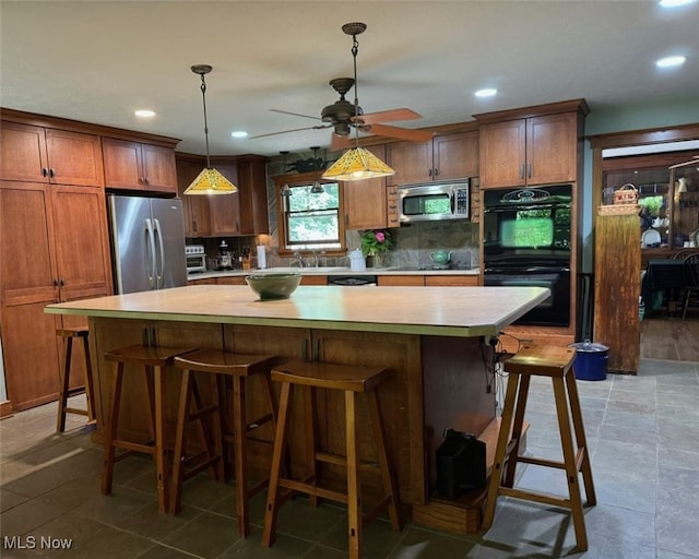 kitchen featuring appliances with stainless steel finishes, decorative light fixtures, backsplash, a center island, and ceiling fan