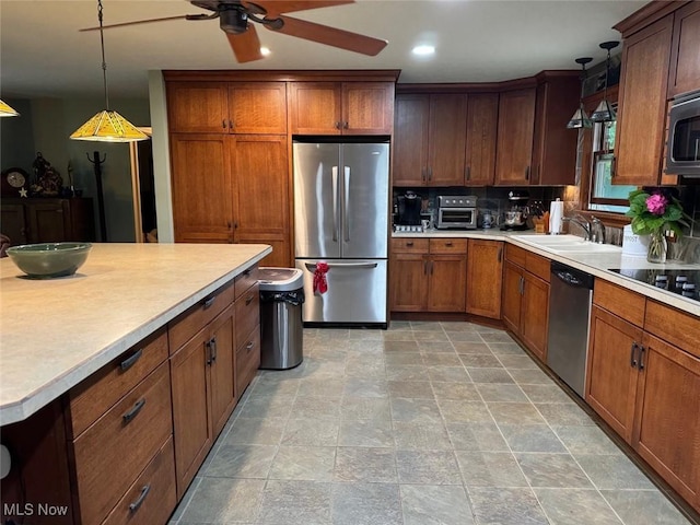 kitchen with sink, ceiling fan, appliances with stainless steel finishes, hanging light fixtures, and tasteful backsplash