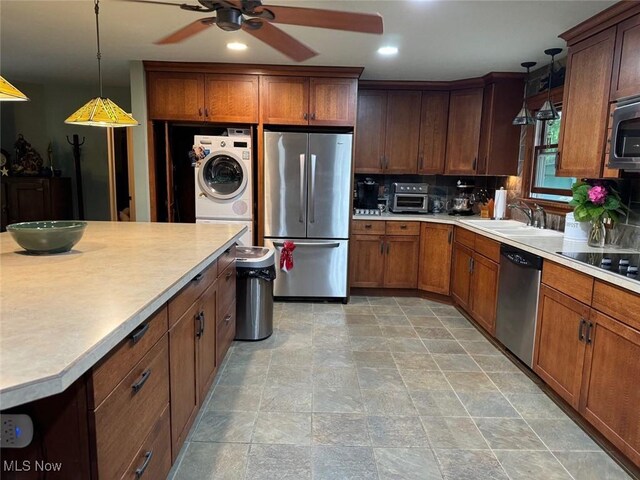 kitchen featuring sink, stacked washer and dryer, decorative light fixtures, ceiling fan, and stainless steel appliances