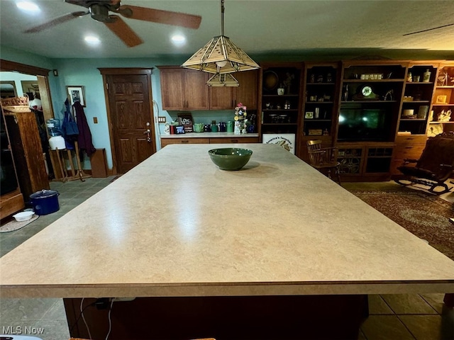 kitchen featuring ceiling fan, hanging light fixtures, and tile patterned floors