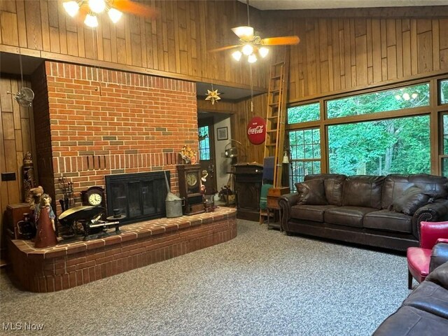 living room featuring carpet floors, high vaulted ceiling, ceiling fan, and wood walls