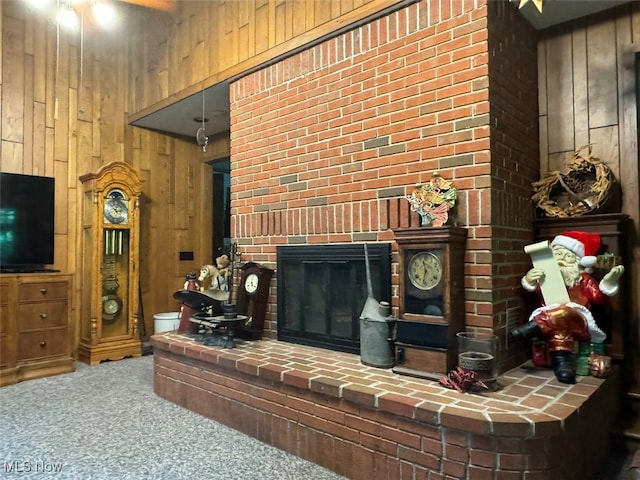 living room with carpet flooring, wood walls, and a brick fireplace